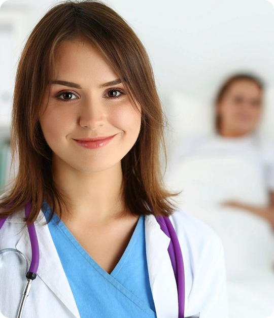 A woman in scrubs and a doctor standing behind her.