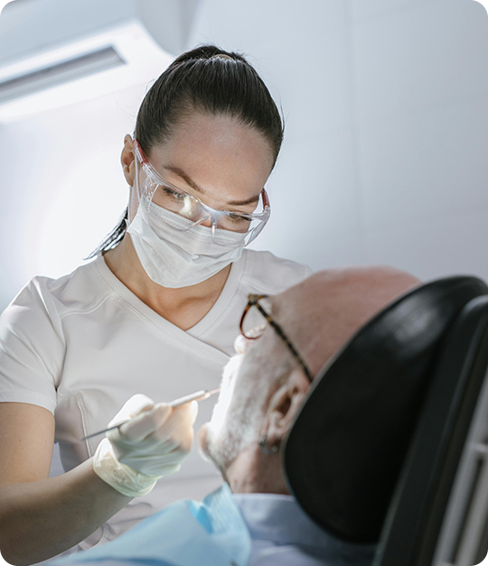 A woman in white shirt and glasses working on man 's face.