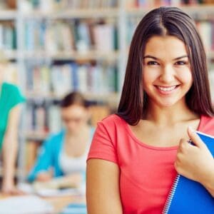A girl is smiling while holding her book.