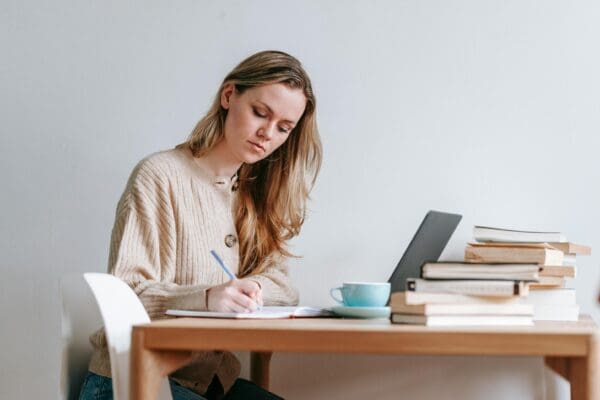 A woman sitting at a table writing on paper.