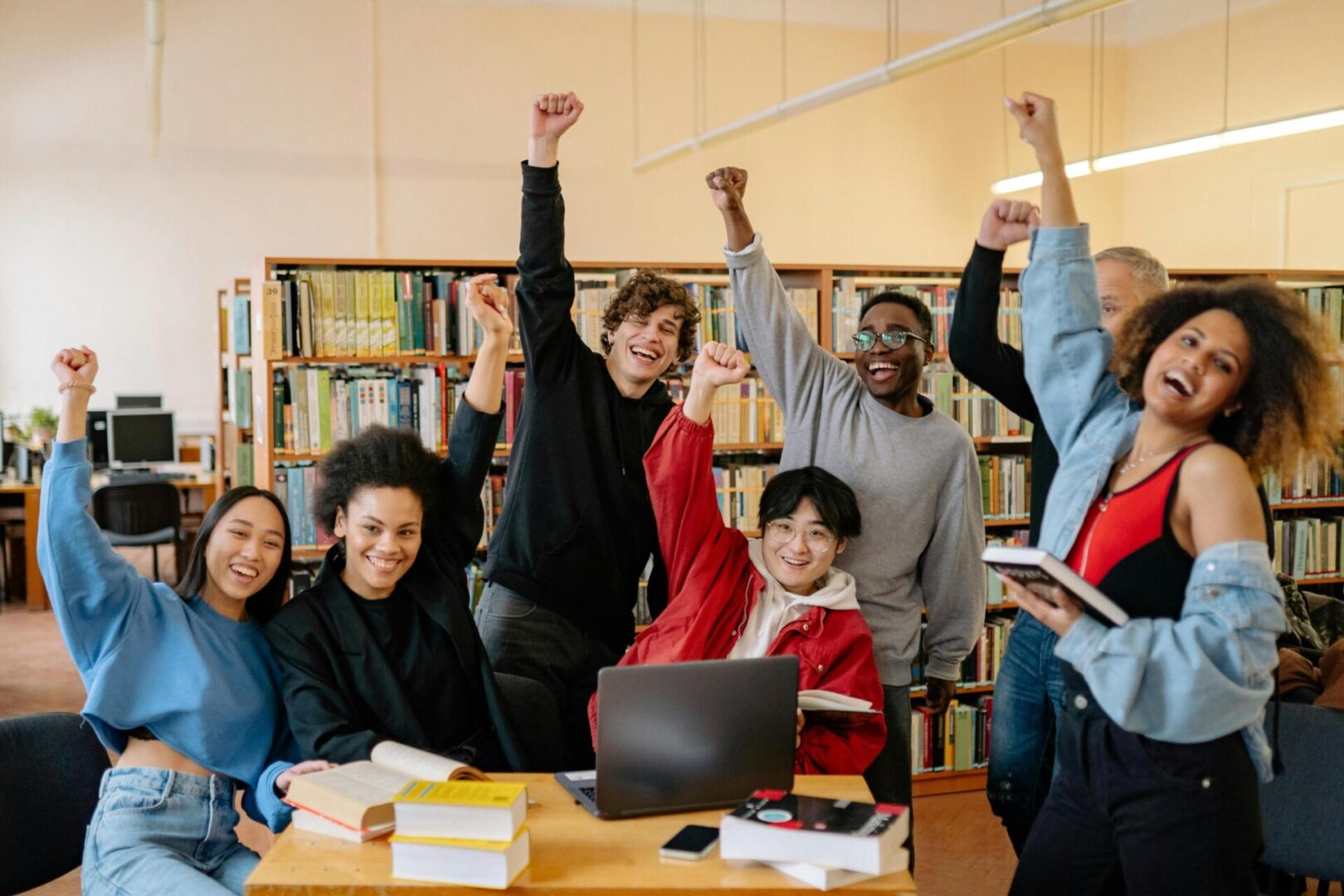 A group of people at a table with arms raised.